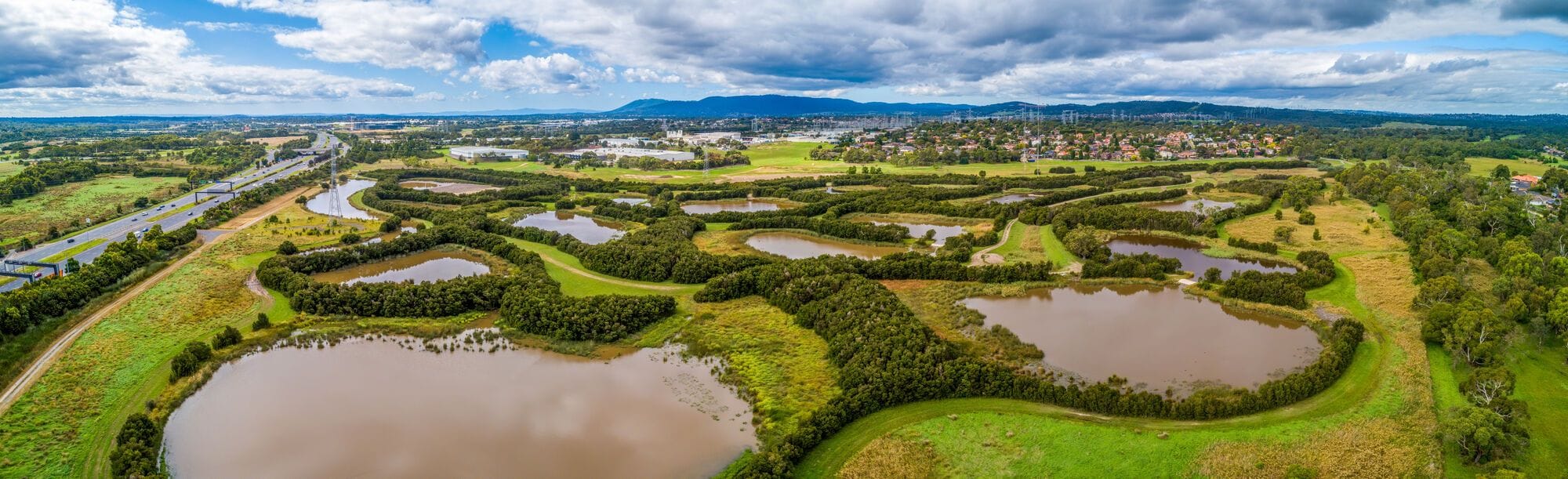 An aerial view of a wide expanse of constructed wetlands and surrounding vegetation.