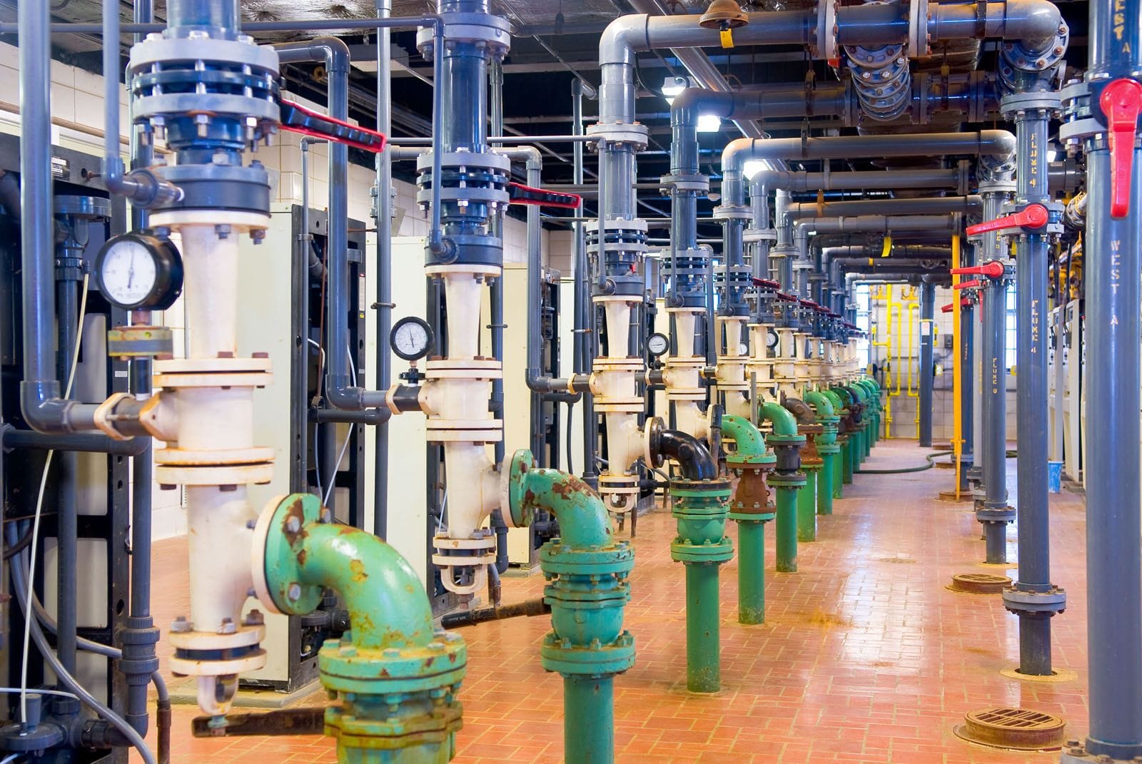 A long row of industrial water utility pipes inside a facility.